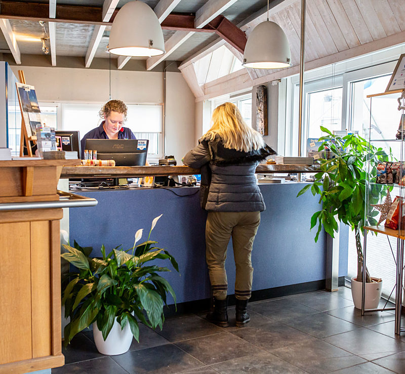 Terschelling Recreatie Receptionist helpt een gast van een vakantiehuis