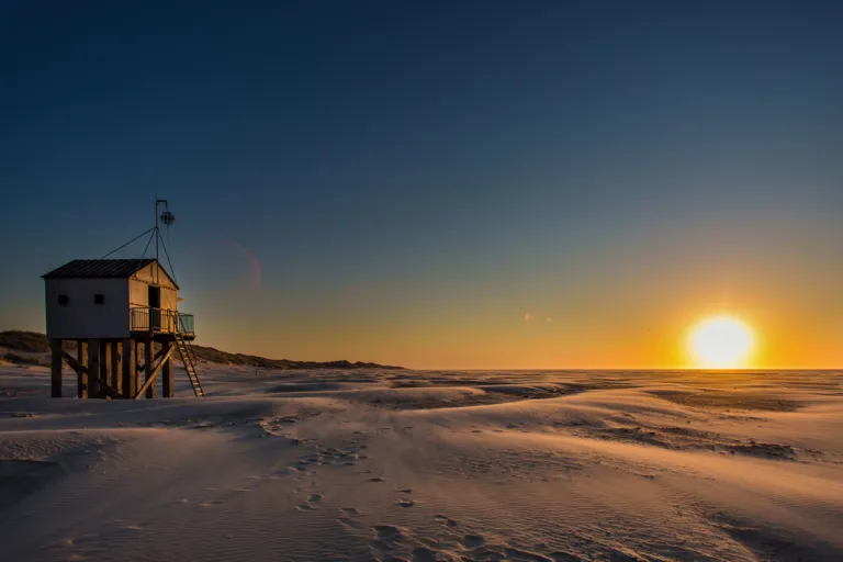 Drenkelingenhuisje bij dorp Oosterend Terschelling op het Noordzeestrand ondergaande zon