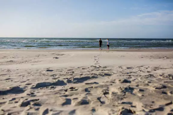 een stel loopt richting de branding op het Noordzeestrand op Terschelling