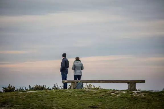 Een stel kijkt naar de zonsondergang op een duin op West-Terschelling