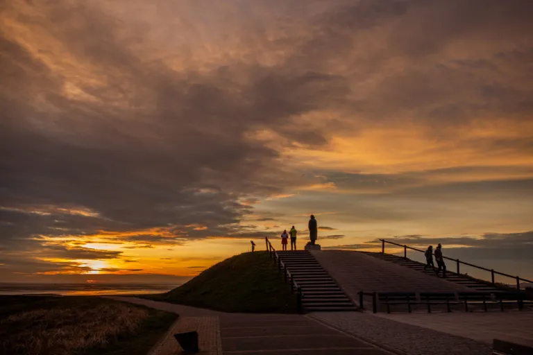 Zonsondergang bij Zeeliedenmonument met enkele bezoekers West-Terschelling