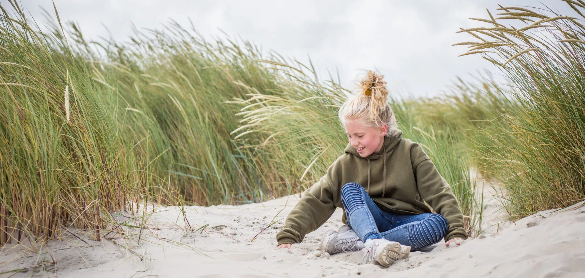 Meisje speelt met zand in de duinen. Gezin naar Terschelling