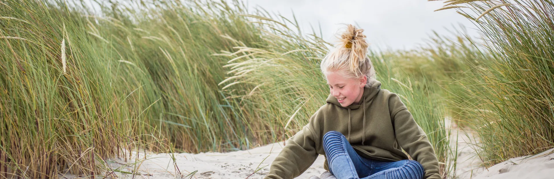 Meisje speelt met zand in de duinen. Gezin naar Terschelling