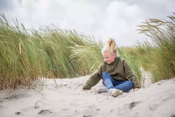 Meisje speelt met zand in de duinen. Gezin naar Terschelling