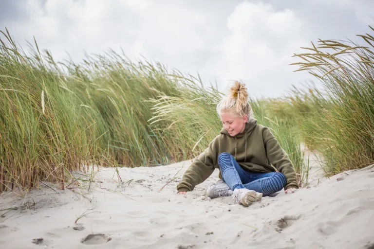 Meisje speelt met zand in de duinen. Gezin naar Terschelling